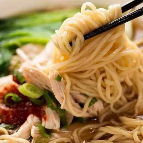 Bowl of delicious Chinese noodle soup with vibrant vegetables and herbs