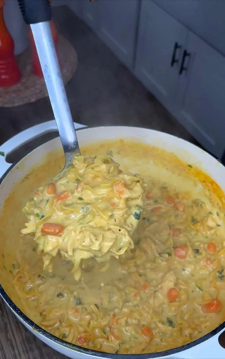Bowl of creamy chicken noodle soup with vegetables and herbs