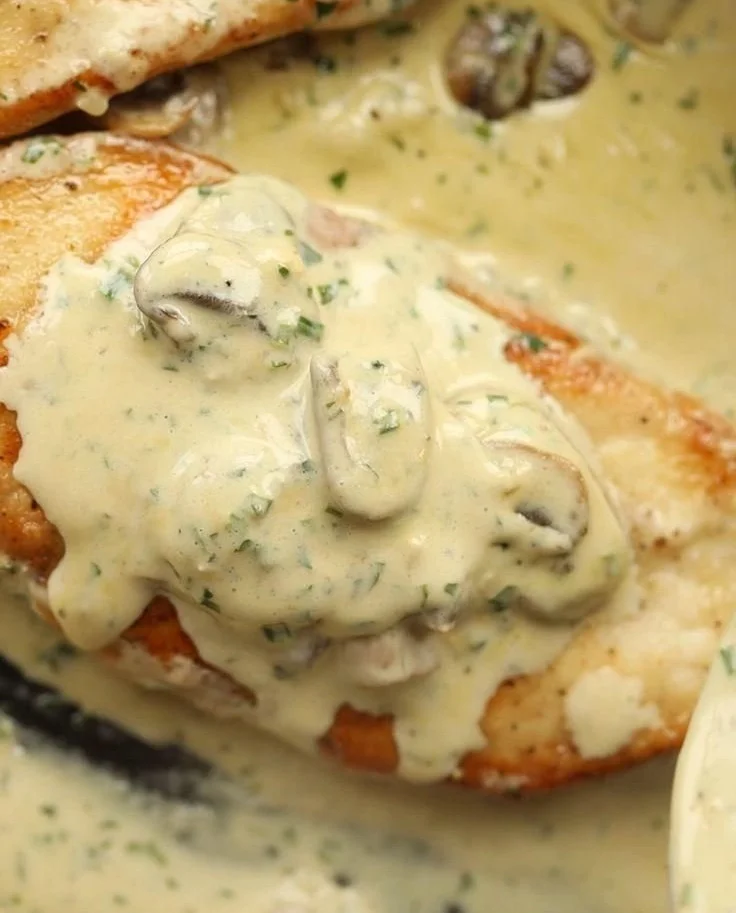 Creamy garlic mushroom chicken served on a plate with herbs.