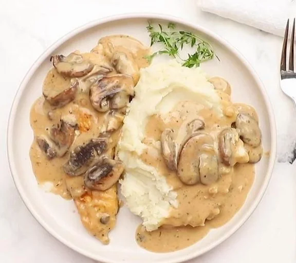 Creamy mushroom chicken served on a plate with fresh herbs