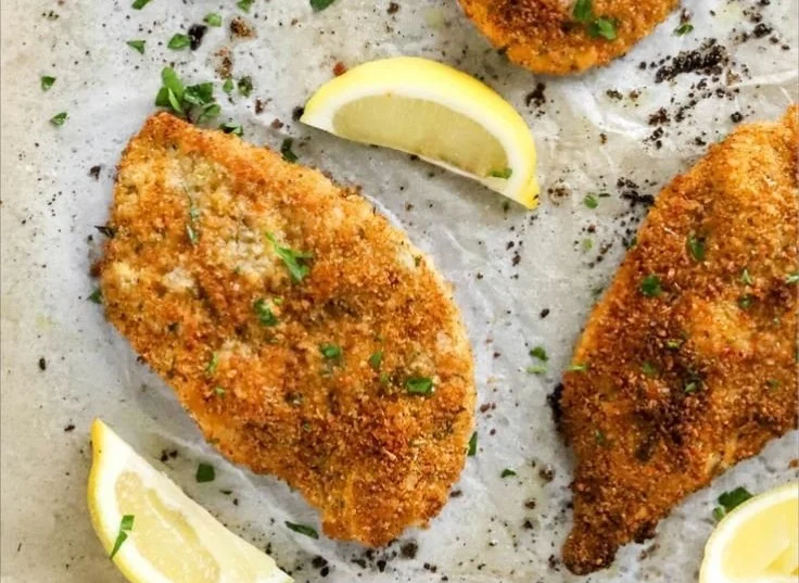 Crispy oven baked chicken cutlets on a plate garnished with herbs