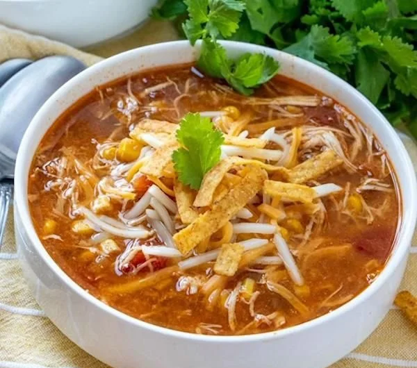 Bowl of creamy Crock Pot chicken tortilla soup garnished with tortilla strips and cilantro