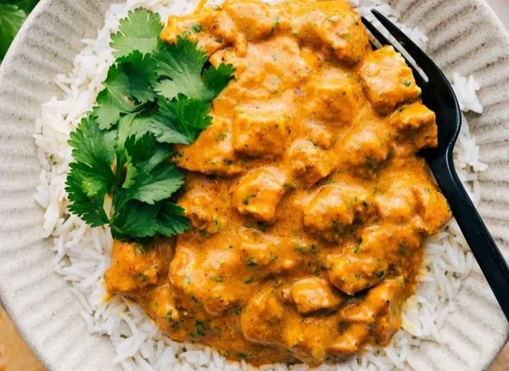 A bowl of creamy Crockpot Butter Chicken garnished with fresh cilantro