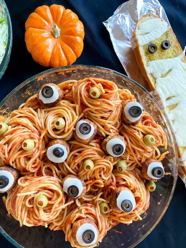 A spooky Halloween dinner setting with themed dishes and decorations.