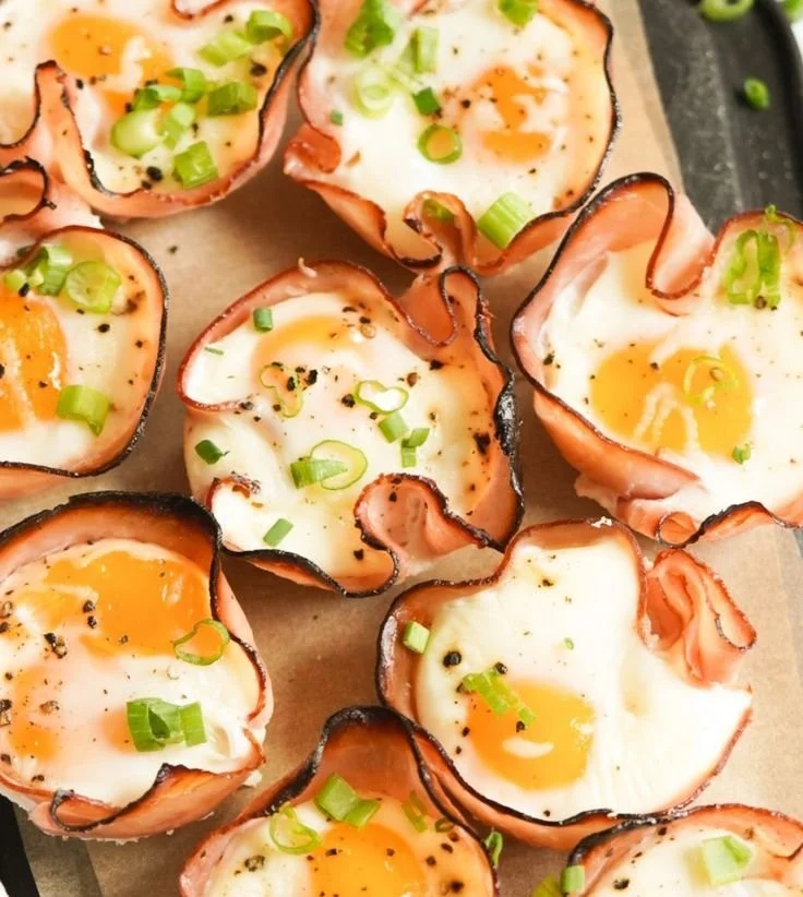 Ham, egg, and cheese muffin cups served on a plate with fresh herbs.