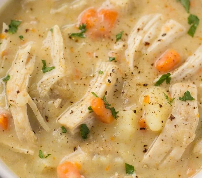 Bowl of healthy chicken pot pie soup garnished with herbs and vegetables