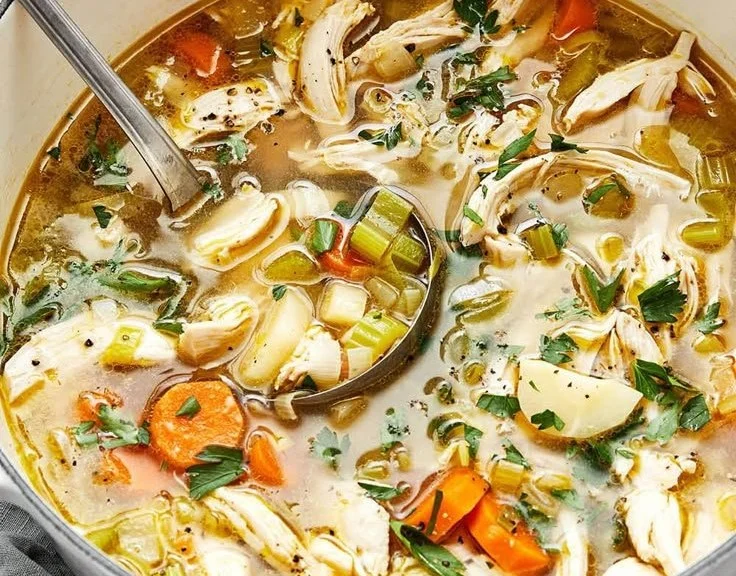 A bowl of homemade chicken soup with vegetables and herbs.
