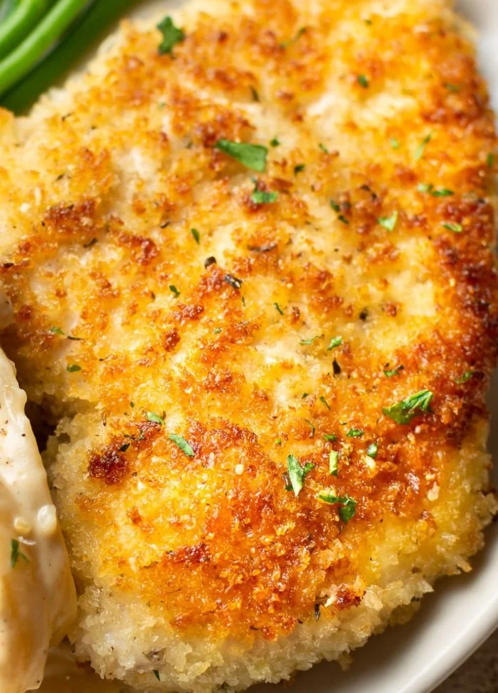 Delicious Parmesan Crusted Chicken served with fresh herbs and vegetables.