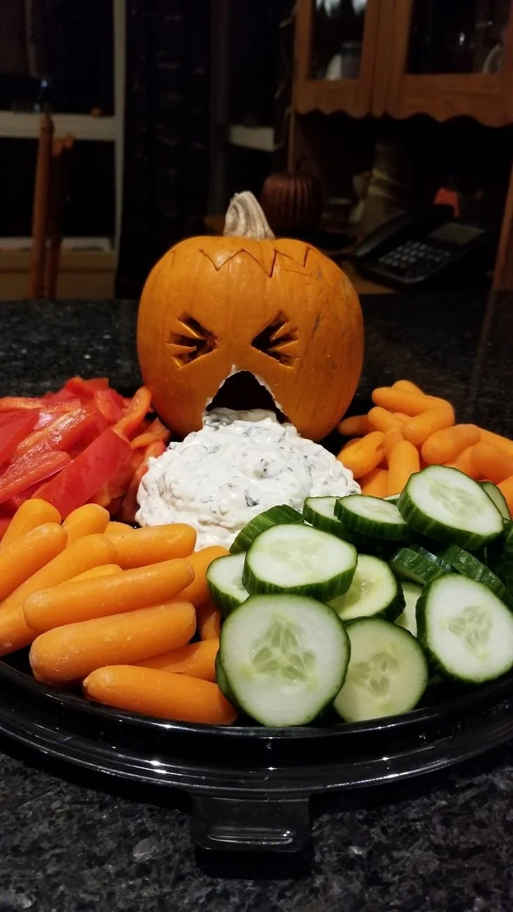 Halloween Puking Pumpkin veggie tray filled with colorful vegetables and dip
