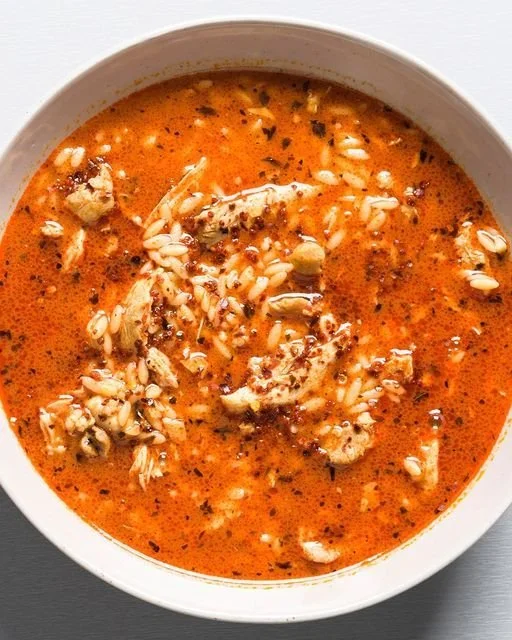 Bowl of Chicken and Orzo Soup with Garlic and Paprika garnished with herbs.