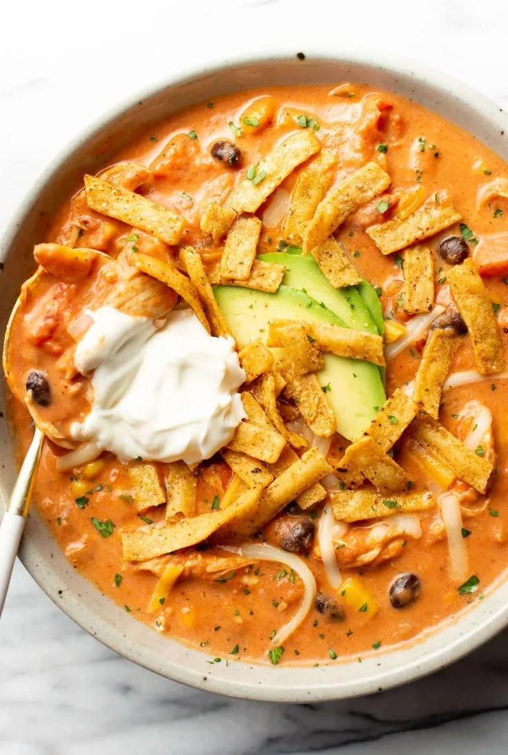 Bowl of creamy chicken tortilla soup topped with tortilla strips and cilantro