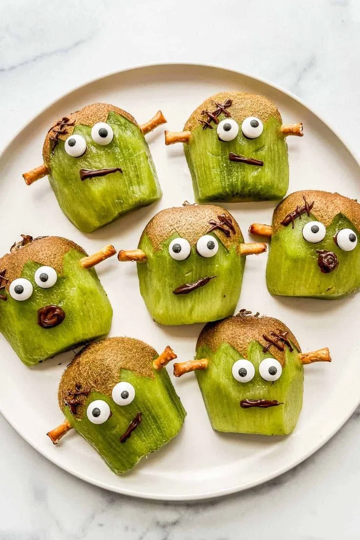 Healthy Halloween party food including Frankenstein Kiwi and decorated pumpkin cookies
